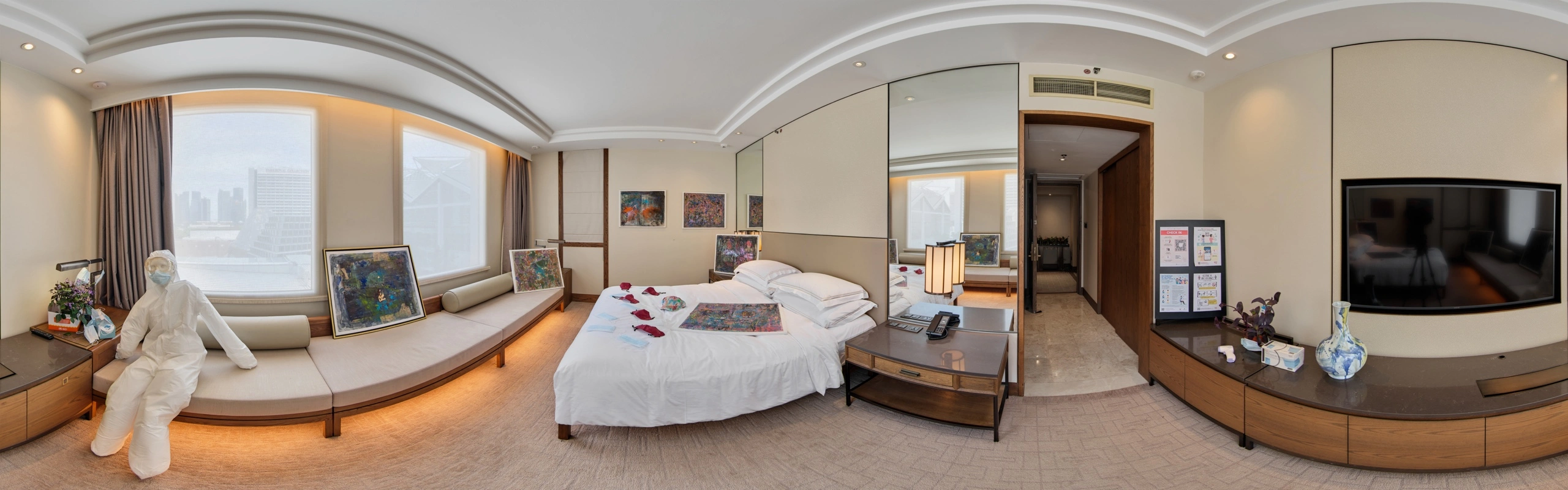 Panoramic view of a #GBK85 exhibition suite with artworks arranged around a bed and an archival protective suit display