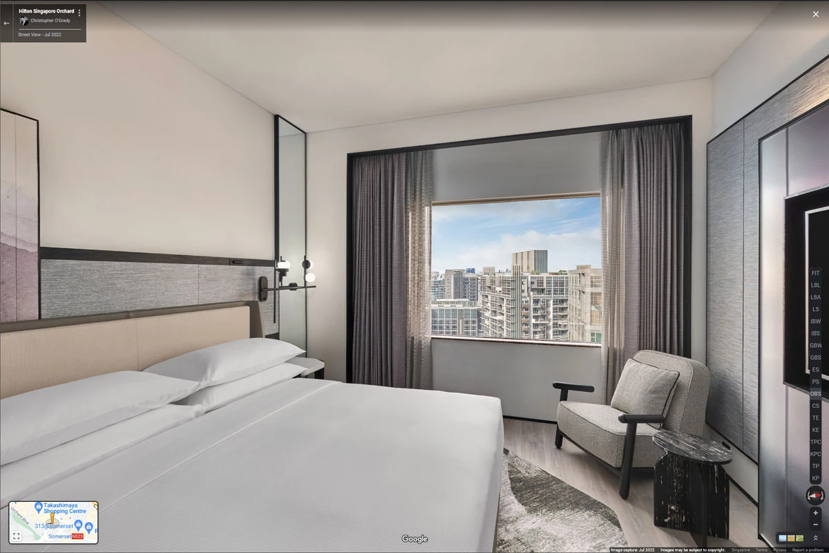Modern guest room with king bed, armchair, and city view window at Hilton Singapore Orchard hotel virtual tour