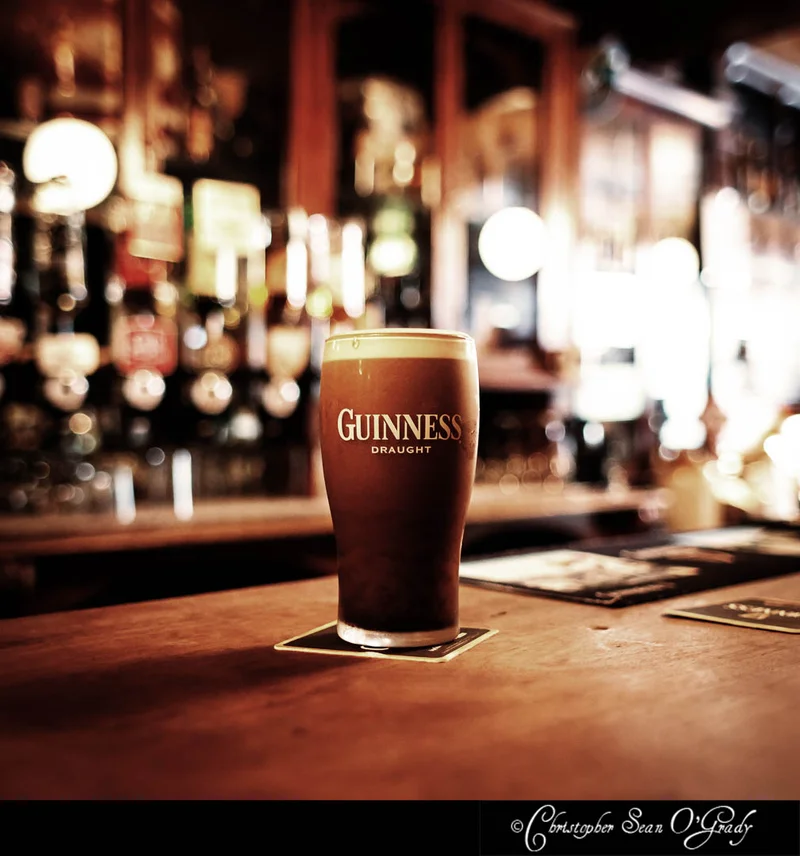 Guinness Draught pint on a wooden bar counter at a warm Irish pub