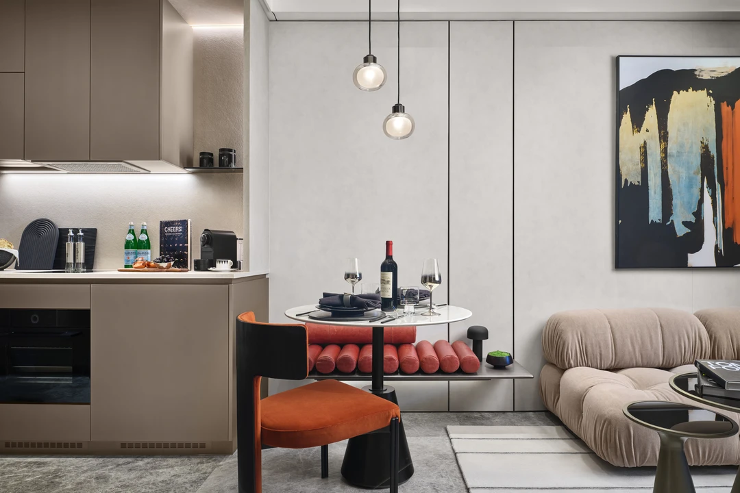 W Residences 1-bedroom showflat dining nook and kitchen with round table, red bench and compact cabinetry, wide view
