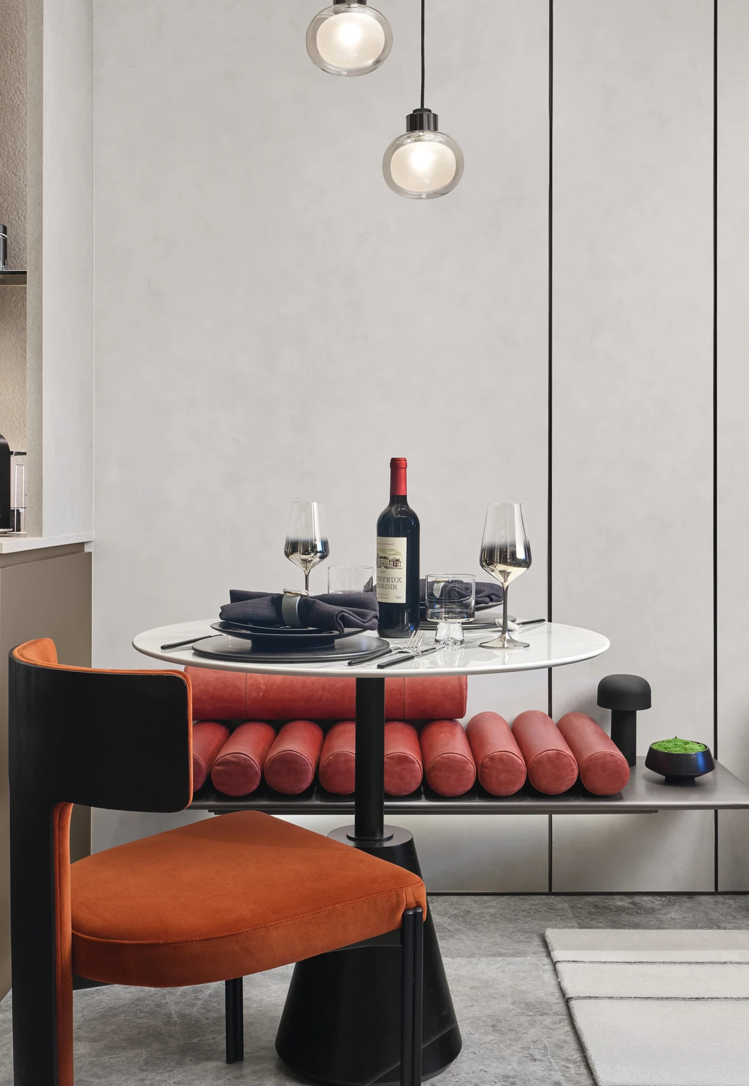 W Residences 1-bedroom showflat dining nook and kitchen with round table, red bench and compact cabinetry, detail view