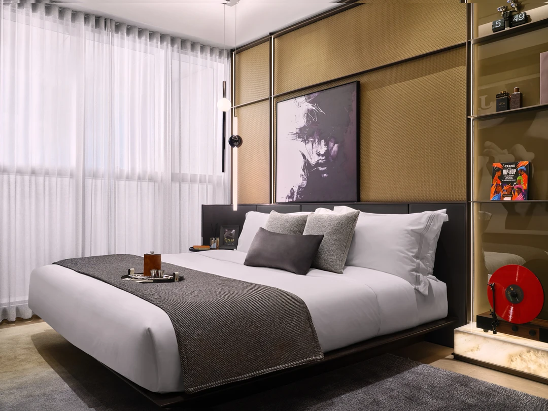 W Residences 1-bedroom showflat bedroom with sheer curtains, layered neutral bedding and black pendant light, wide view
