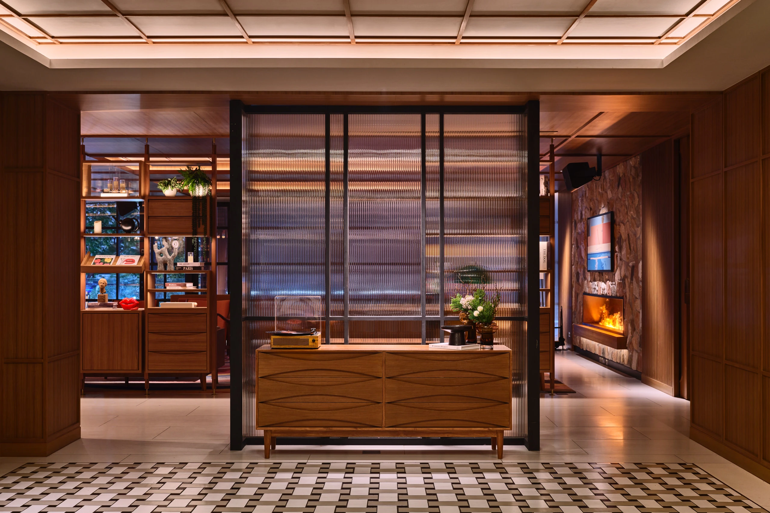 Entrance hallway with walnut credenza, glass partition, geometric tiled floor, and built-in timber shelving