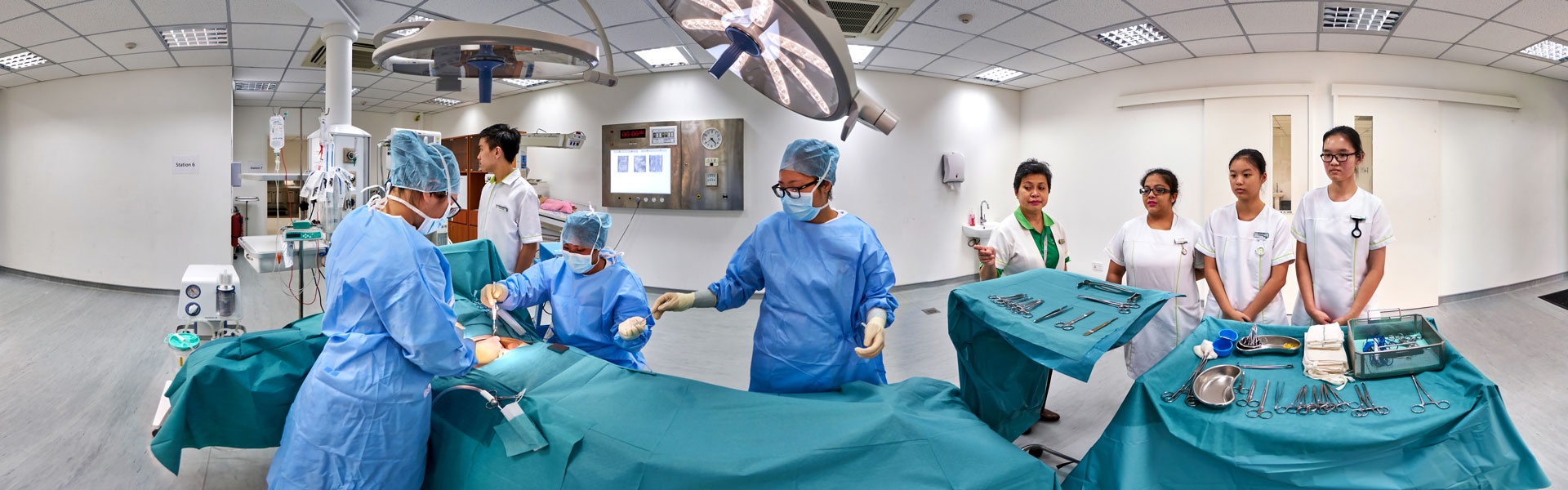 360 panorama of Ngee Ann Polytechnic simulated operating theatre with nursing students in surgical scrubs and instrument trays