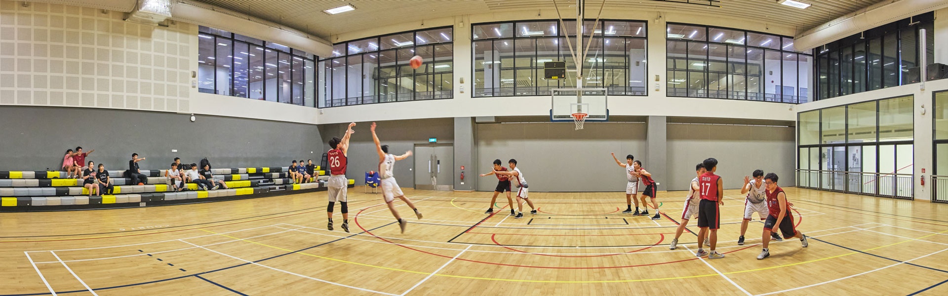 360 panorama of SUTD indoor sports hall with students playing basketball, timber court and glazed upper gallery