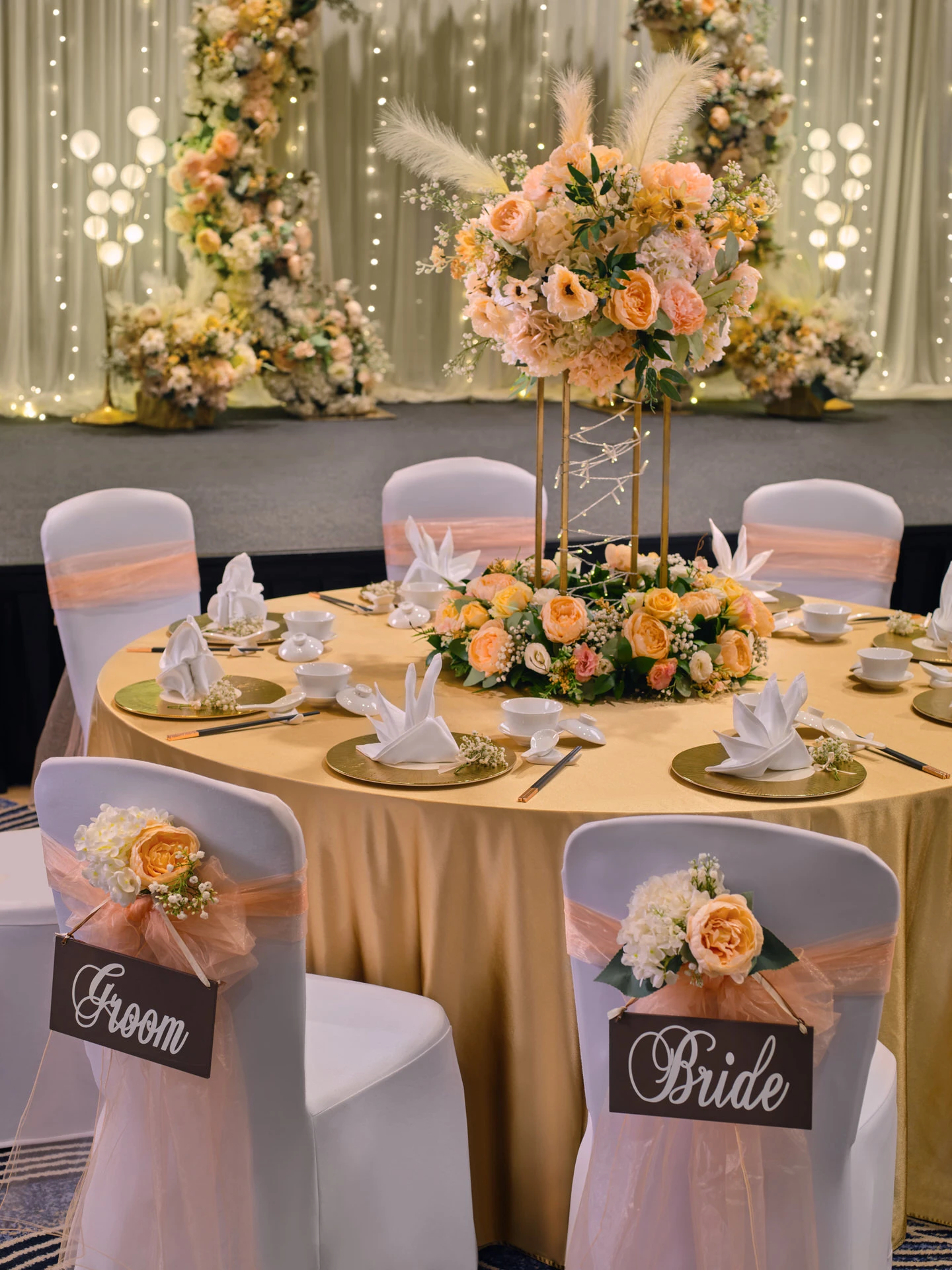 Head table with four-pillar gold centrepiece, peonies and fairy lights - voco Orchard Singapore wedding photography