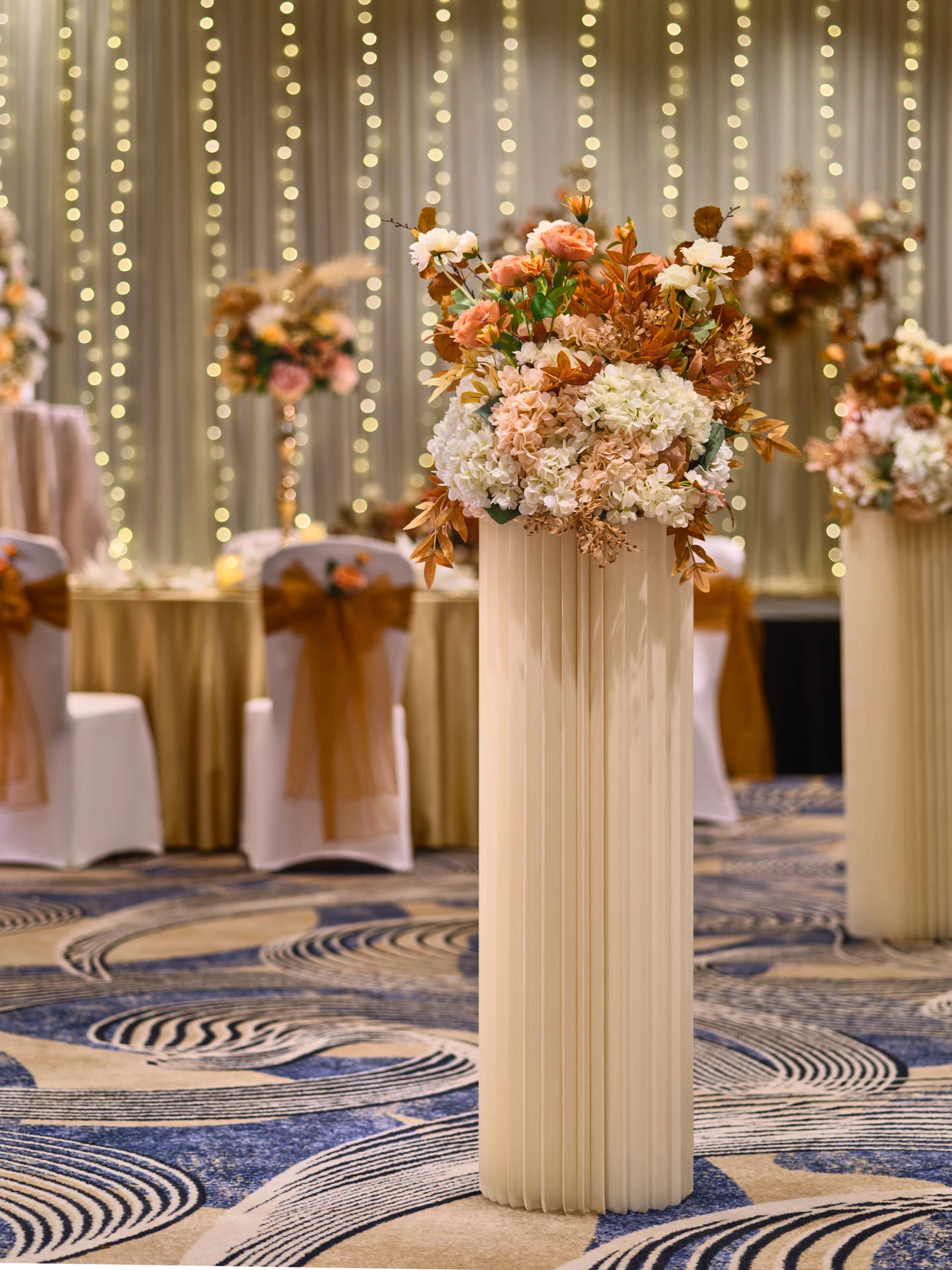 Autumn floral pedestal with dried botanicals and copper foliage on ballroom carpet - voco Orchard Singapore event photography