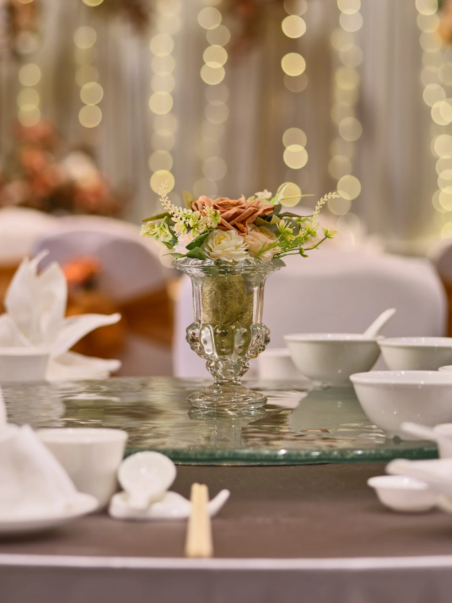 Glass urn centrepiece with terracotta roses and fairy-light bokeh - voco Orchard Singapore wedding photography