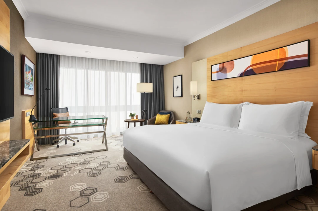 King room with light wood headboard, abstract art and leather armchair
