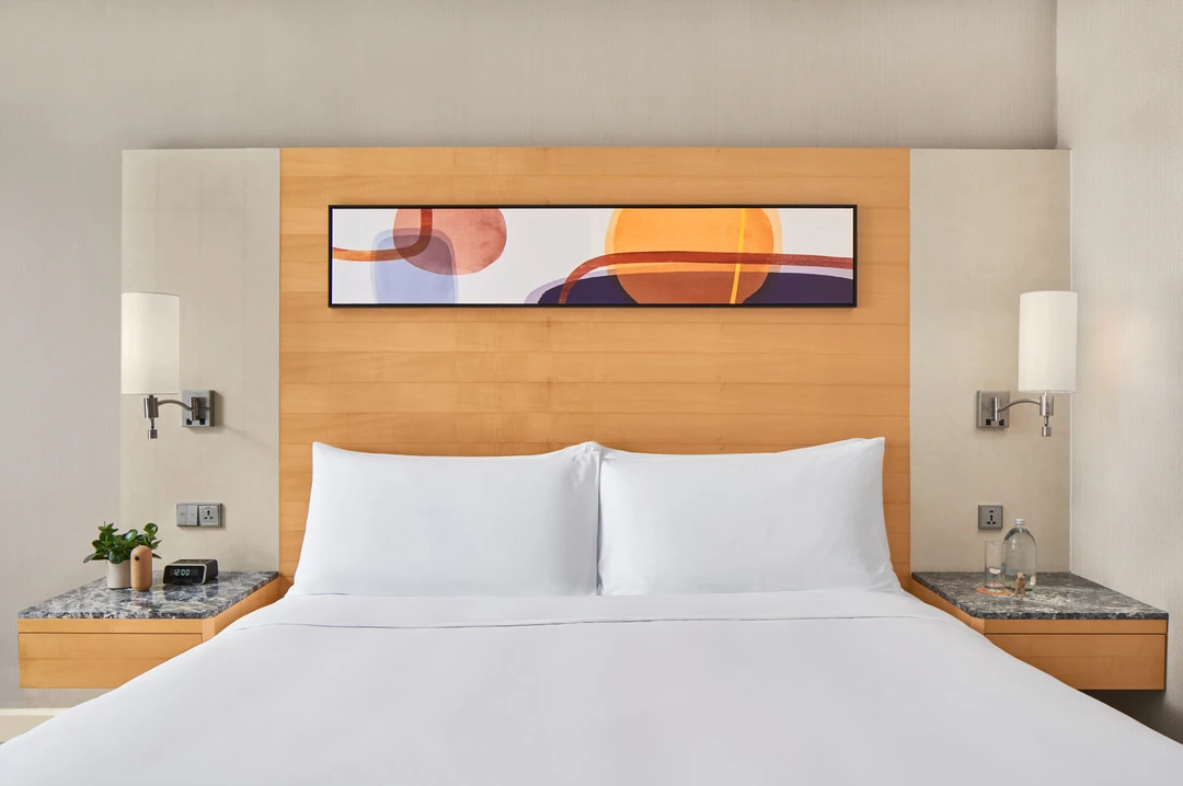 King bed with abstract painting, marble nightstands and chrome sconces