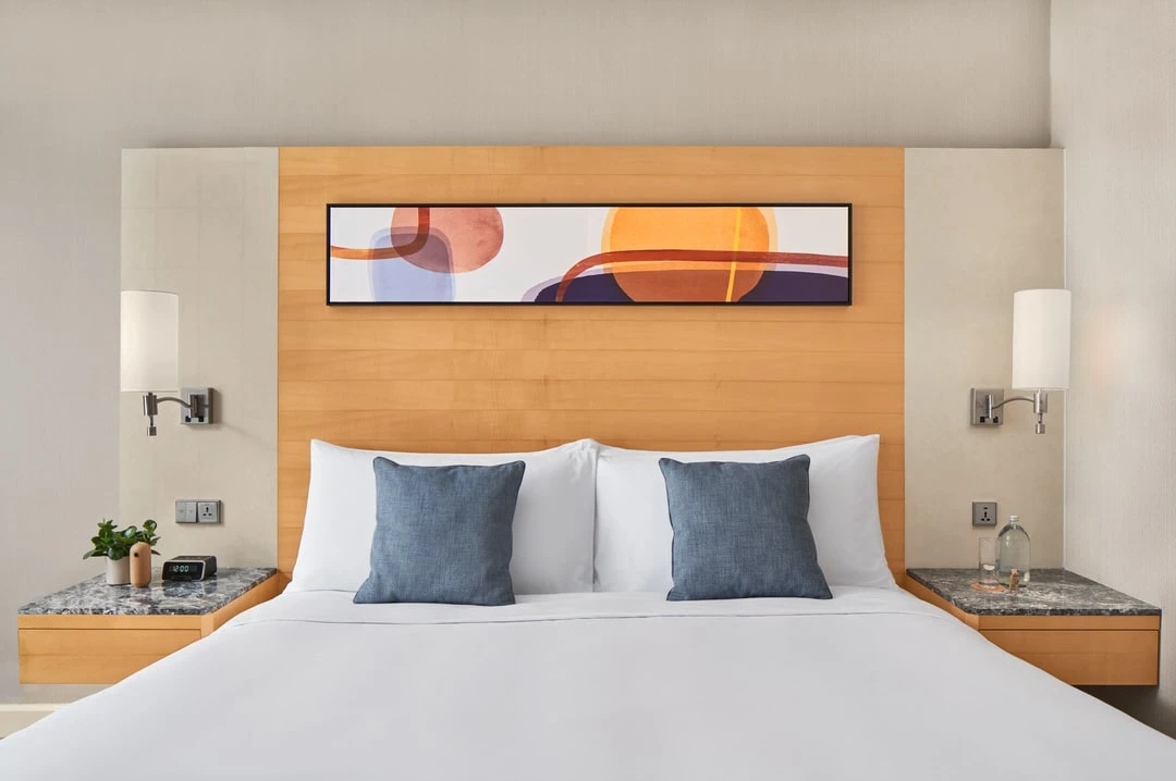 Symmetrical king bed with blue cushions and panoramic abstract artwork
