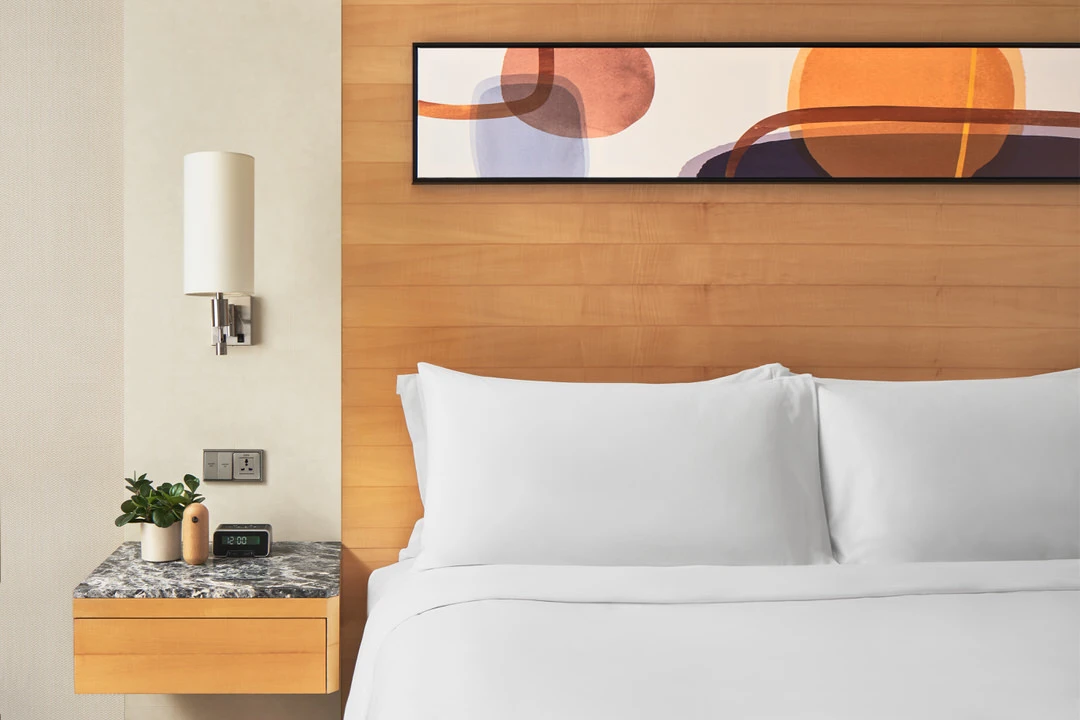 Bedside detail with maple headboard, marble nightstand and chrome sconce