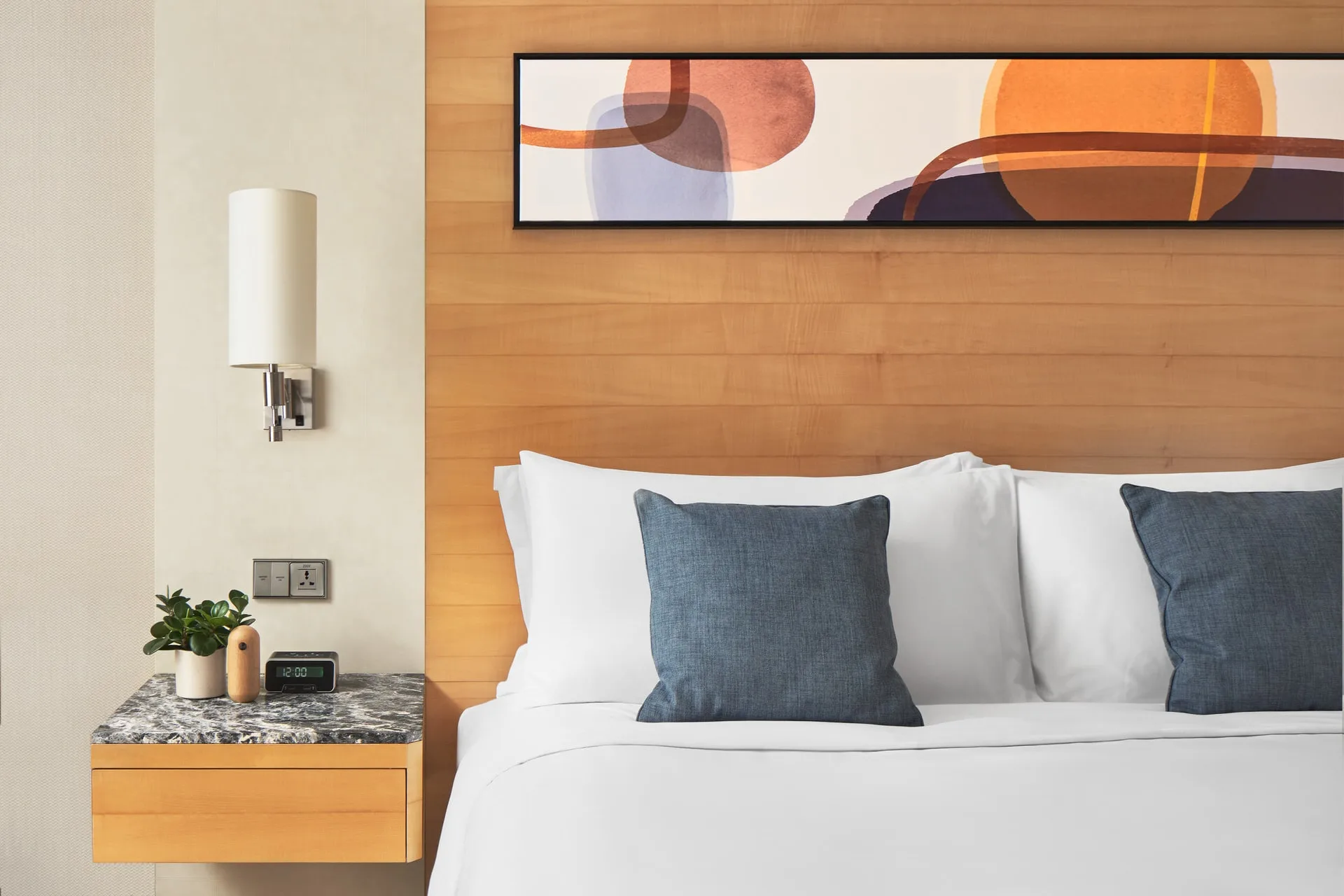 Blue accent cushions with abstract art and frosted glass sconce