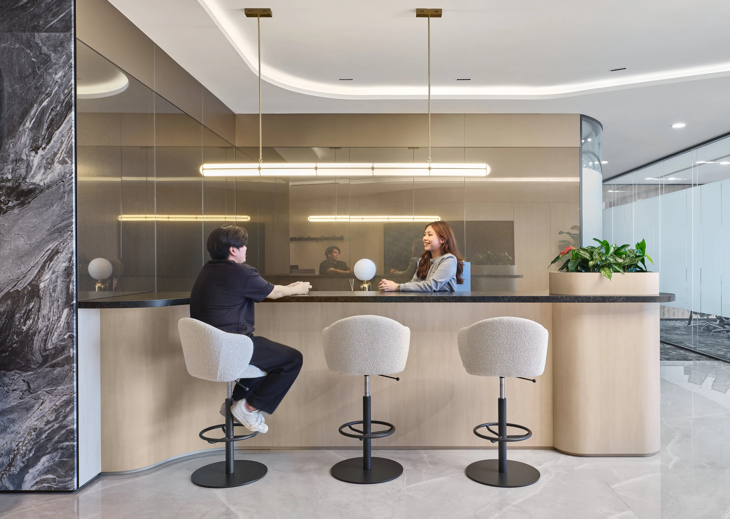 High-top bar counter with bouclé stools, globe lamps and brass pendants