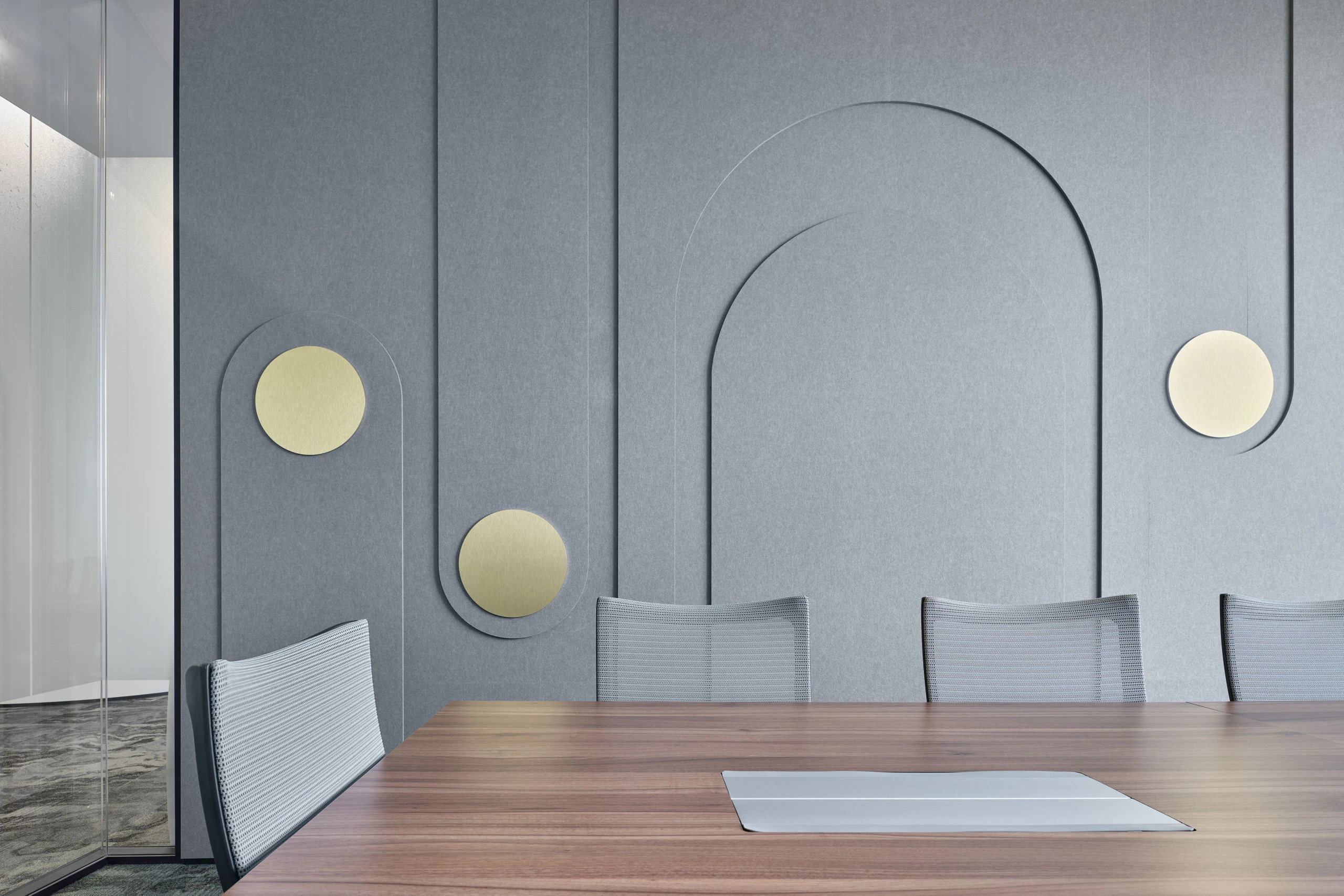 Meeting room with sculpted felt acoustic wall and brass disc sconces