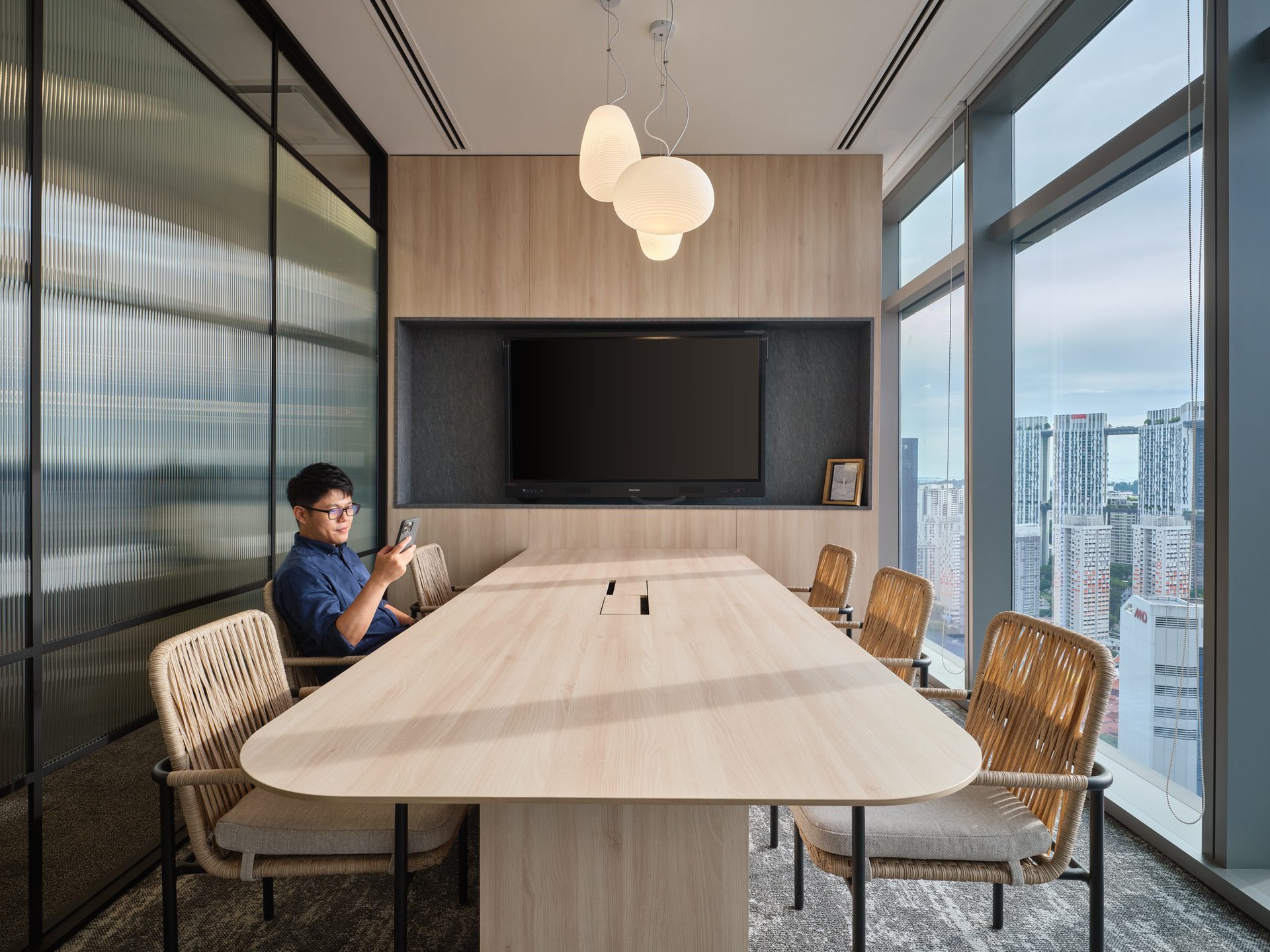 Meeting room with rattan chairs, timber wall and Singapore skyline view