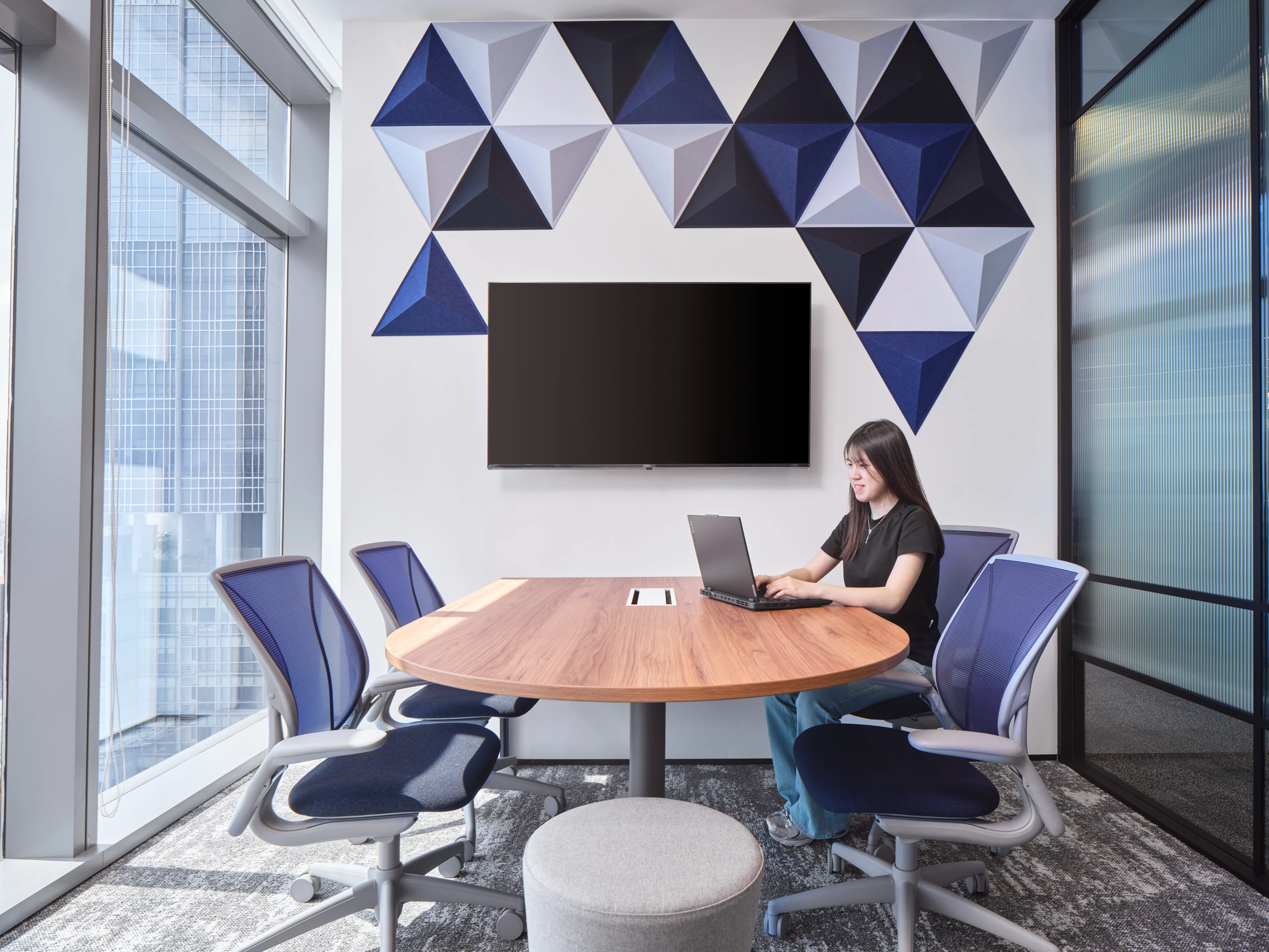 Meeting room with 3D triangular acoustic panels and blue mesh chairs