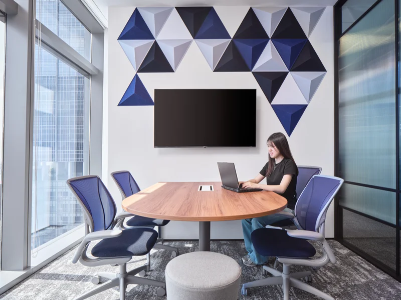 Meeting room with 3D triangular acoustic panels and blue mesh chairs