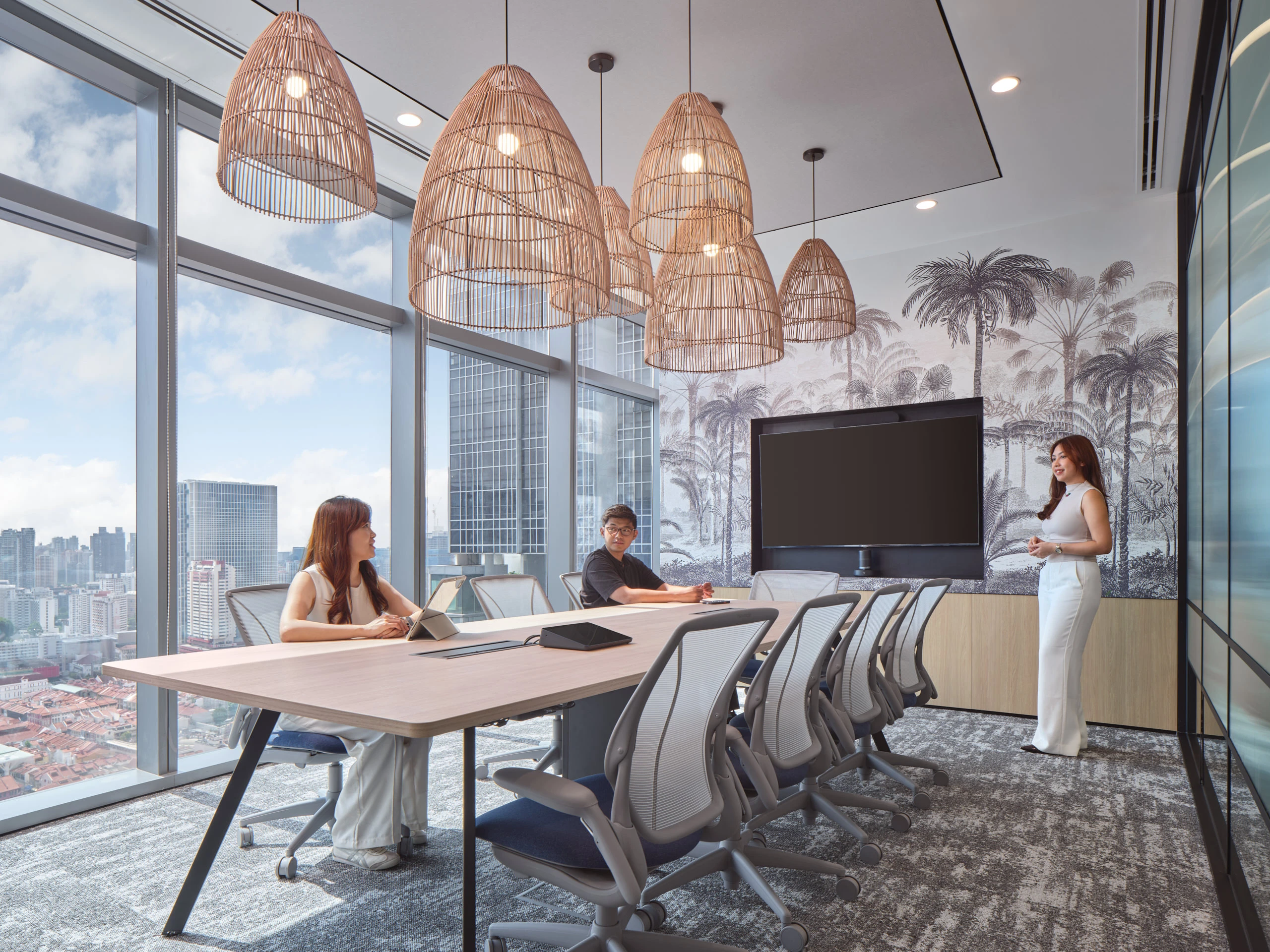 Boardroom with palm mural, rattan pendants and corner glazing