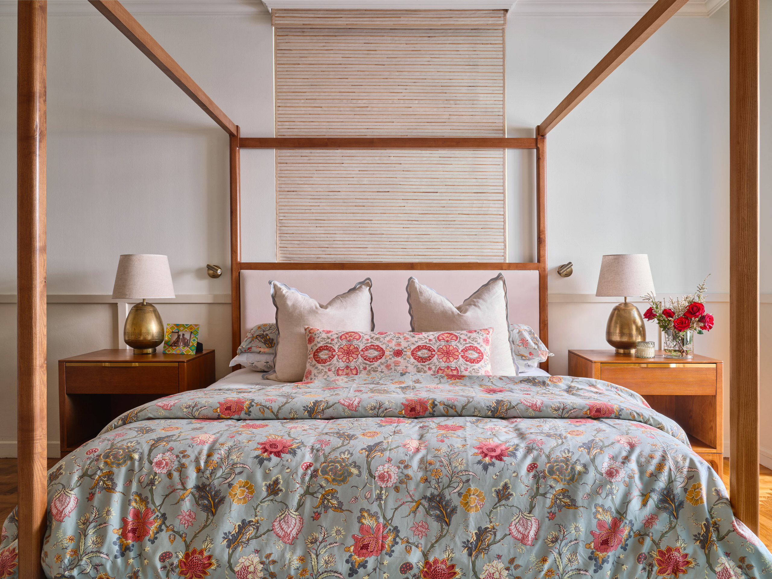 Residential interior design photography of a serene bedroom in East Coast Singapore, featuring a four-poster bed with floral bedding and warm lighting.