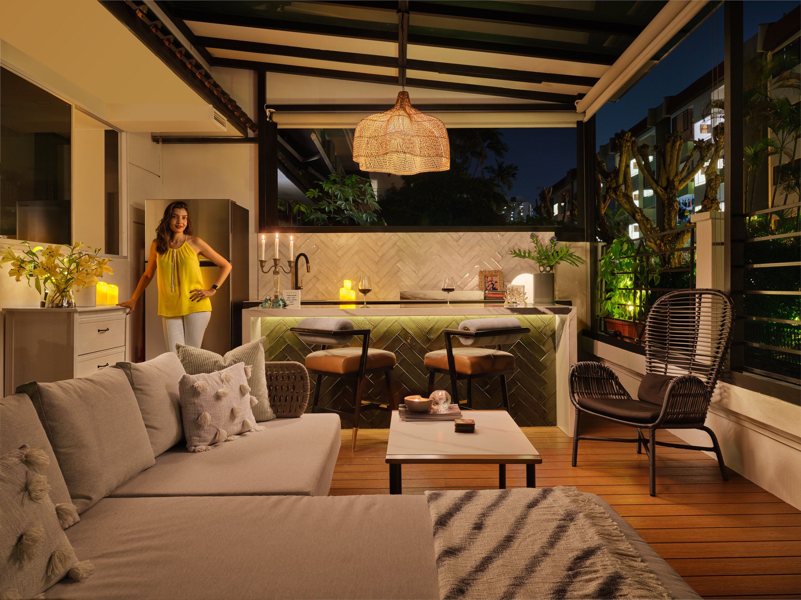 Residential interior design photography of an outdoor bar area in East Coast Singapore, with warm lighting, woven textures, and a cozy seating arrangement.