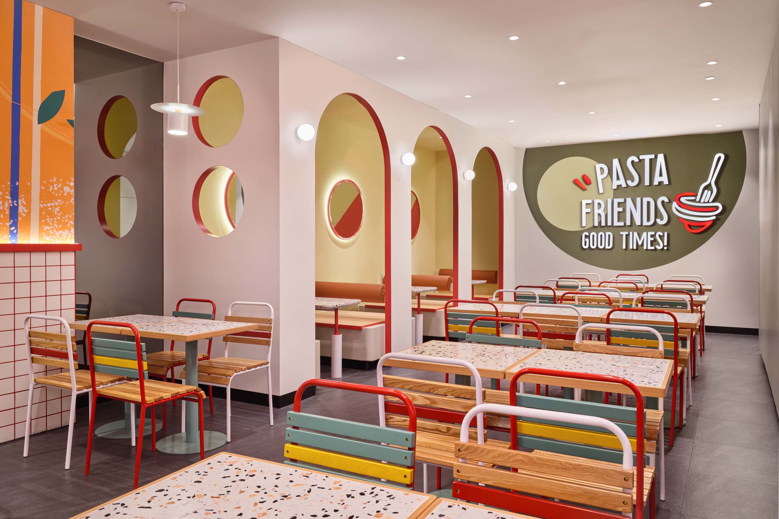PastaMania Lot One booth seating with red arched alcoves, circular porthole windows, and Pasta Friends wall graphic